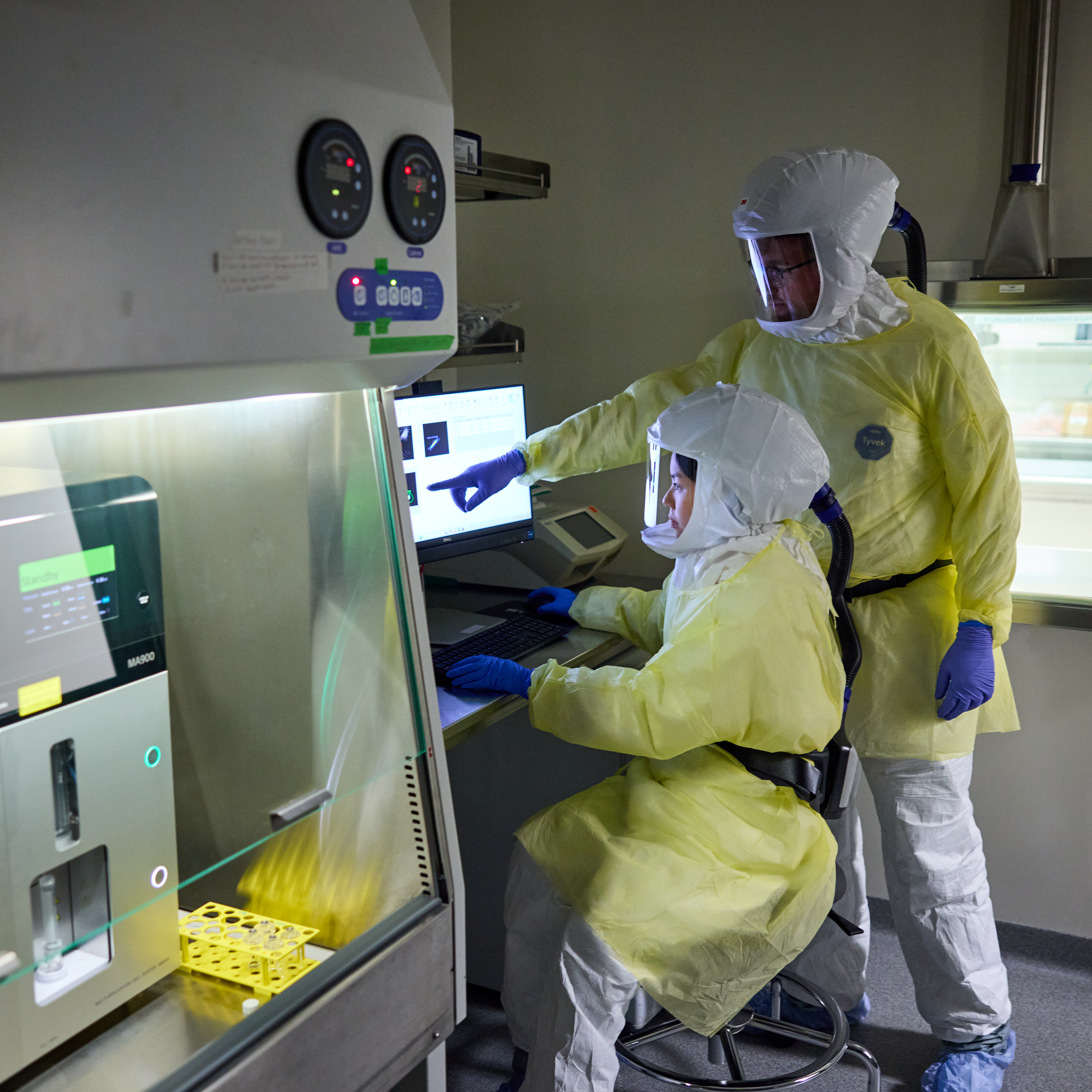 MSTP student Truc Pham, a trainee in Mike Diamond’s lab, and Matt Cain, PhD, work in the BSL3 lab on August 1, 2025. It was Pham’s first time in the lab, so Cain was training her on how to properly don PPE for the research.